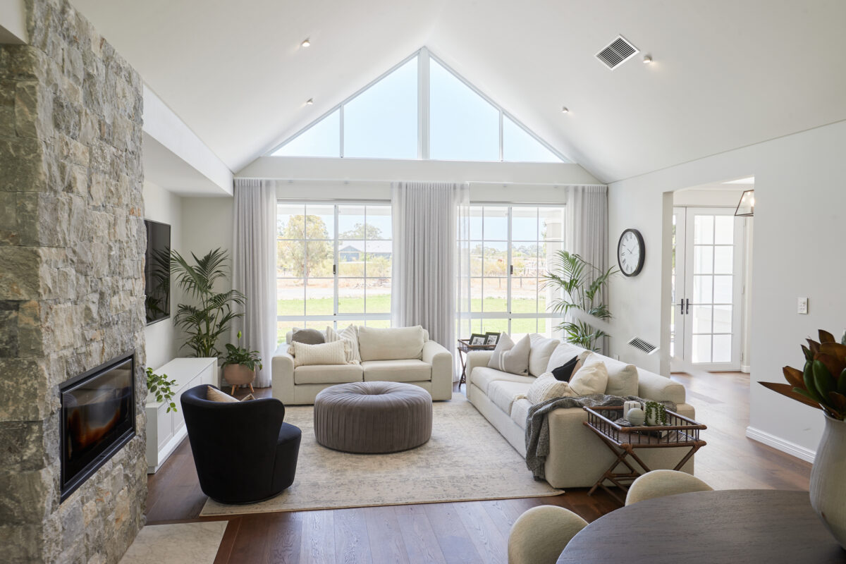 Raked ceilings over the living zone create a voluminous sense of space, while a stone-feature wall houses a built-in fireplace.