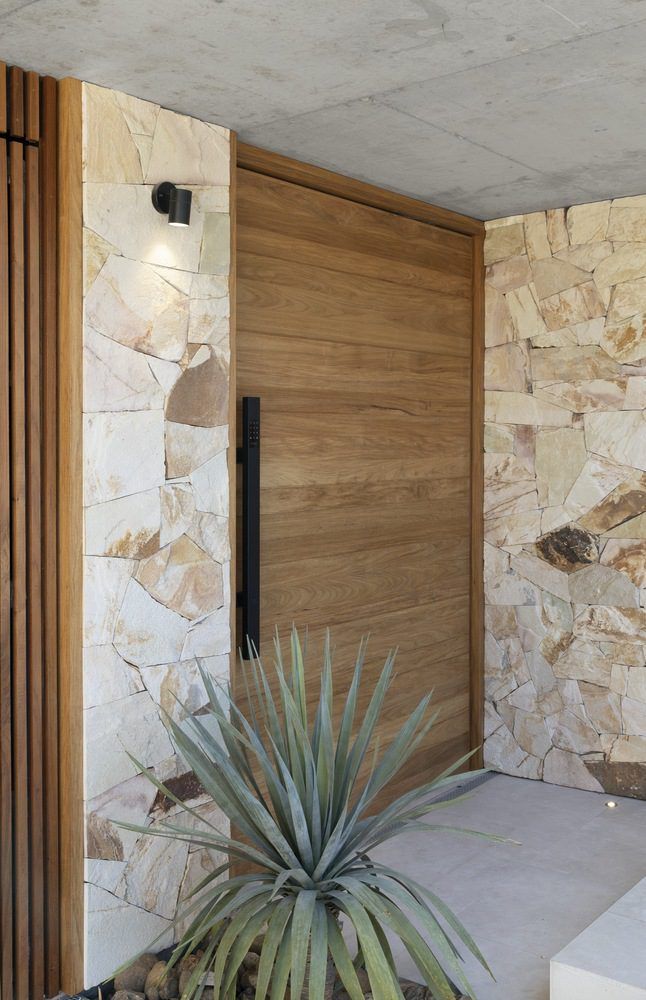 Large wooden front door and entryway with stone wall cladding either side