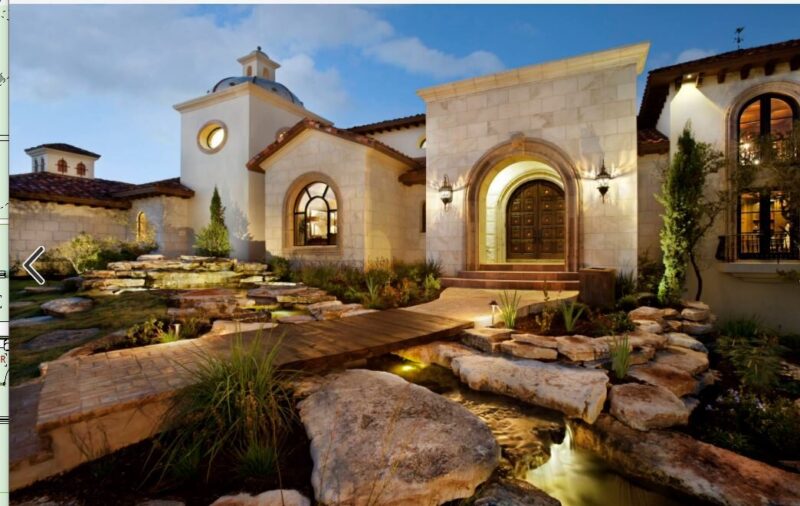 mediterranean inspired villa with arched wooden front door and water feature with a bridge