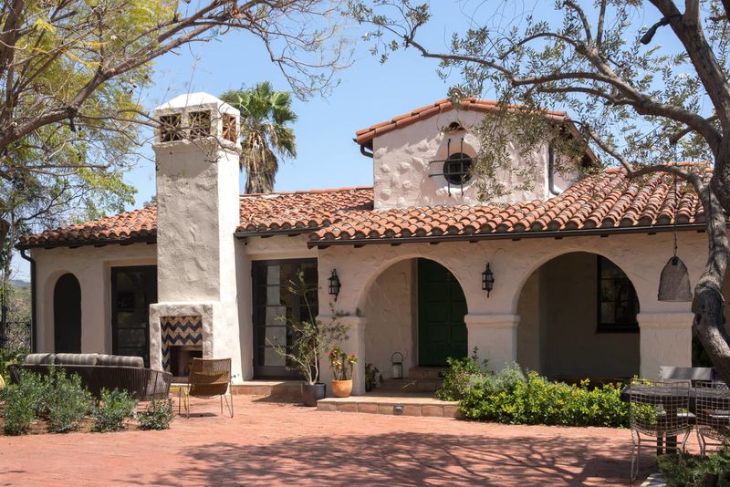 mediterranean villa with tiled roof, chimney and arched entryways