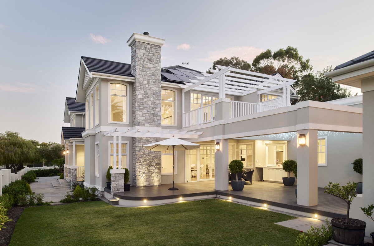 double storey hampton manor with stone wall chimney and garden lights