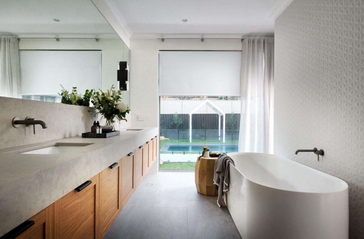 freestanding bathtub with double sink wooden vanity. overlooking big floor to ceiling window with a view of the pool