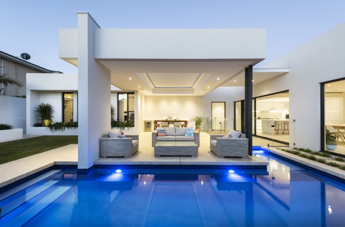 swimming pool next to covered alfresco area with wicker dining set