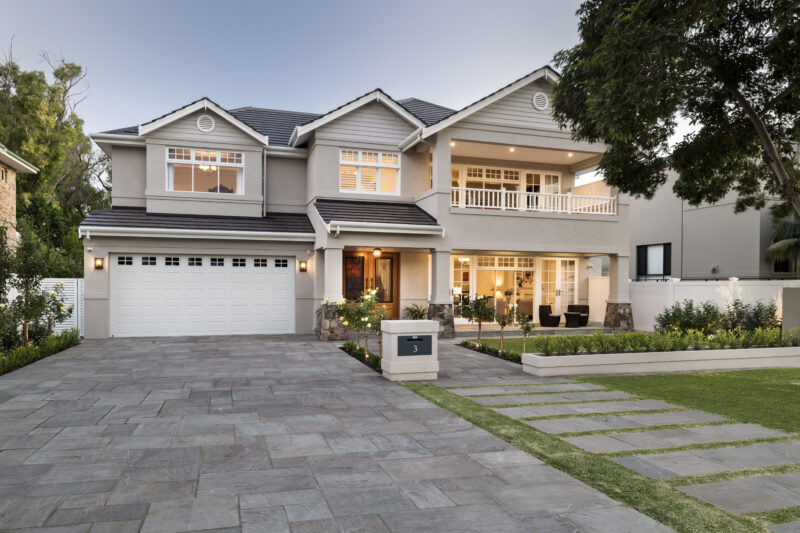 external shot of a double storey hamptons home with a double garage and stone paved driveway