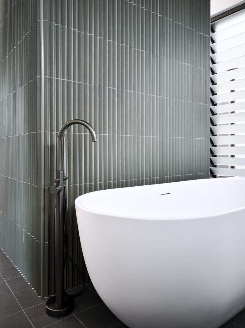 Bathroom with green tiled wall and freestanding bath