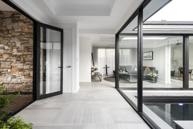 Front entrance to the inside of the home with dark accents and glass doors and windows.