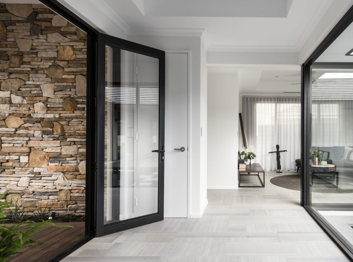 Front entrance to the inside of the home with dark accents and glass doors and windows.