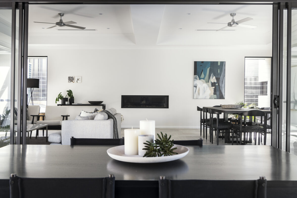 View from the dining table to the living area featuring luxury furnishings, and dark accents for a contemporary feel. This contemporary custom home built by Oswald Homes.