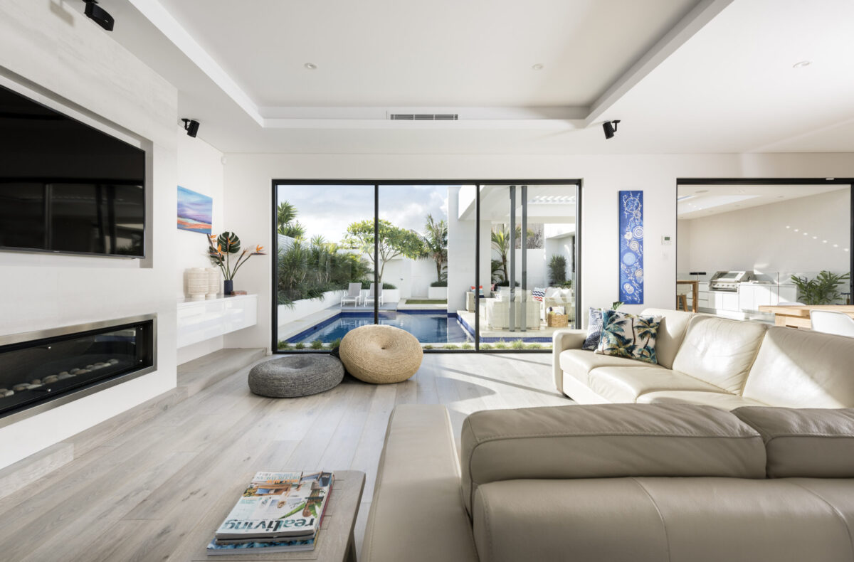 Living room with linear fireplace opening to a pool courtyard