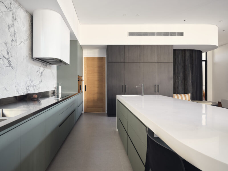 Kitchen with sage green cabinetry, marble splashback and white stone island bench