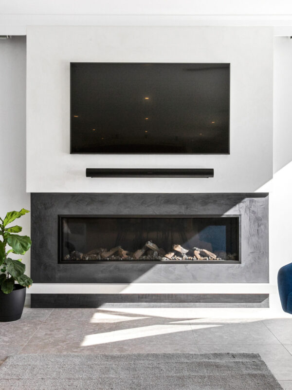 Oswald Homes luxury home design in Perth, living room with linear gas fireplace, stone hearth and blue velvet armchair